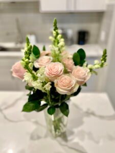 An arrangement of blush pink roses and greenery for a grieving ritual