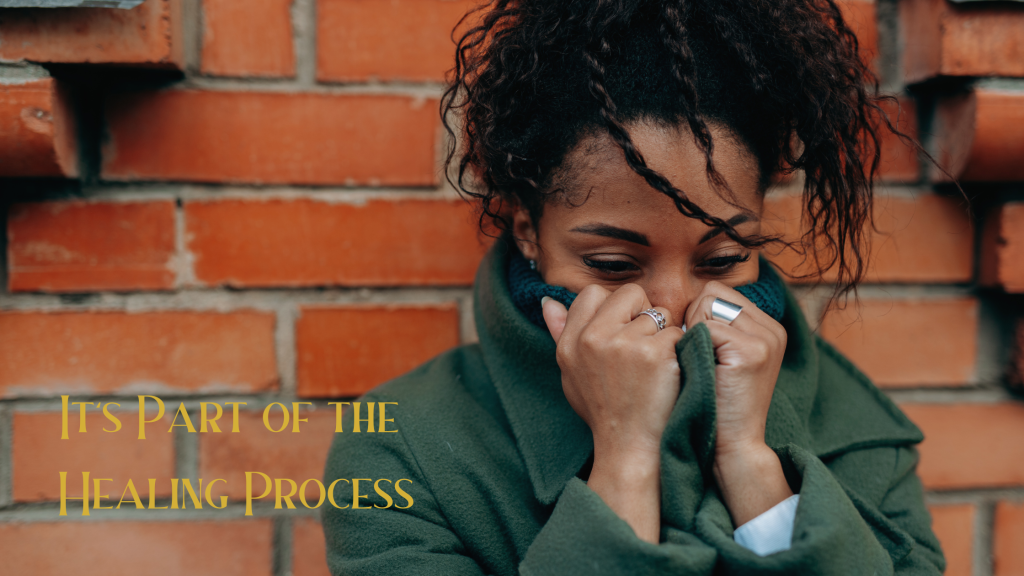 African American woman with her sweater pulled up over her face while grieving