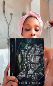 woman in a bathtub reading a book and eating a chocolate covered strawberry