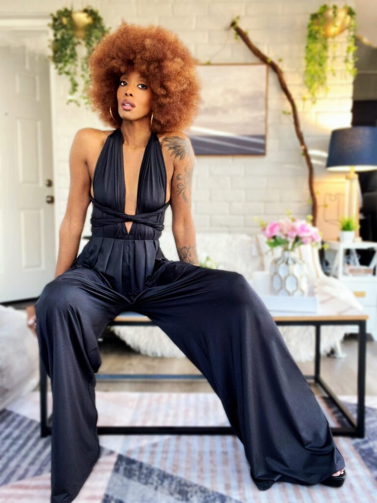 African American woman in a black jumpsuit sitting on a table