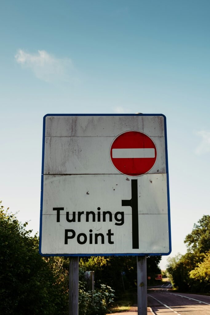 red and white road sign that reads turning point