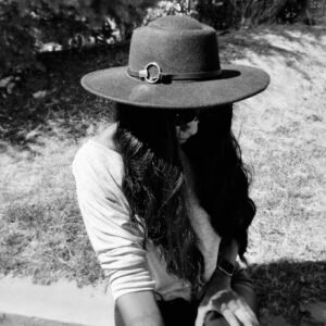 black and white photo of a woman looking down feeling guilt while wearing a hat