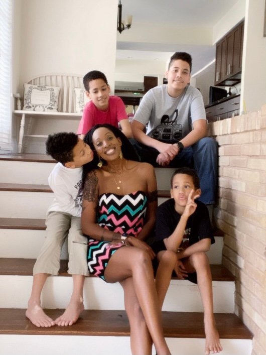 woman posing on the stairs with her four young sons