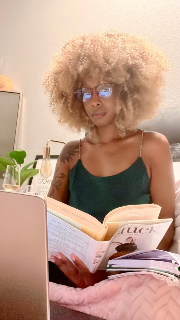 Woman sitting in bed with a laptop and book