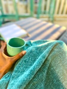 A hand holding a coffee cup on a balcony at sunrise