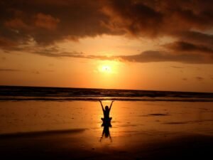 Peaceful meditation silhouette at sunset on a serene beach.