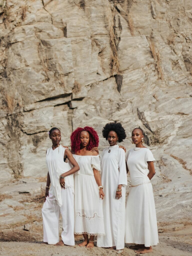 Four women in white dresses confidently posing against a rugged rock backdrop.